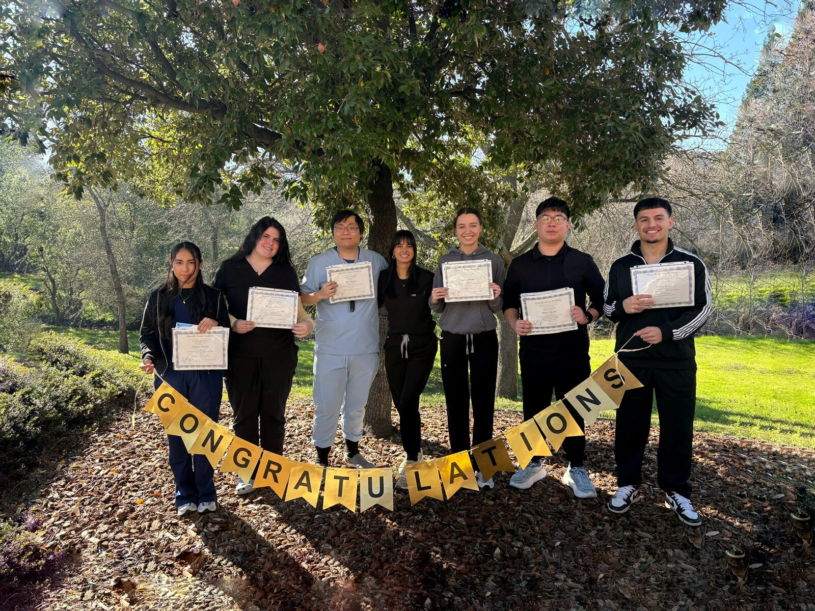 Students celebrating course completion certificates outside the academy